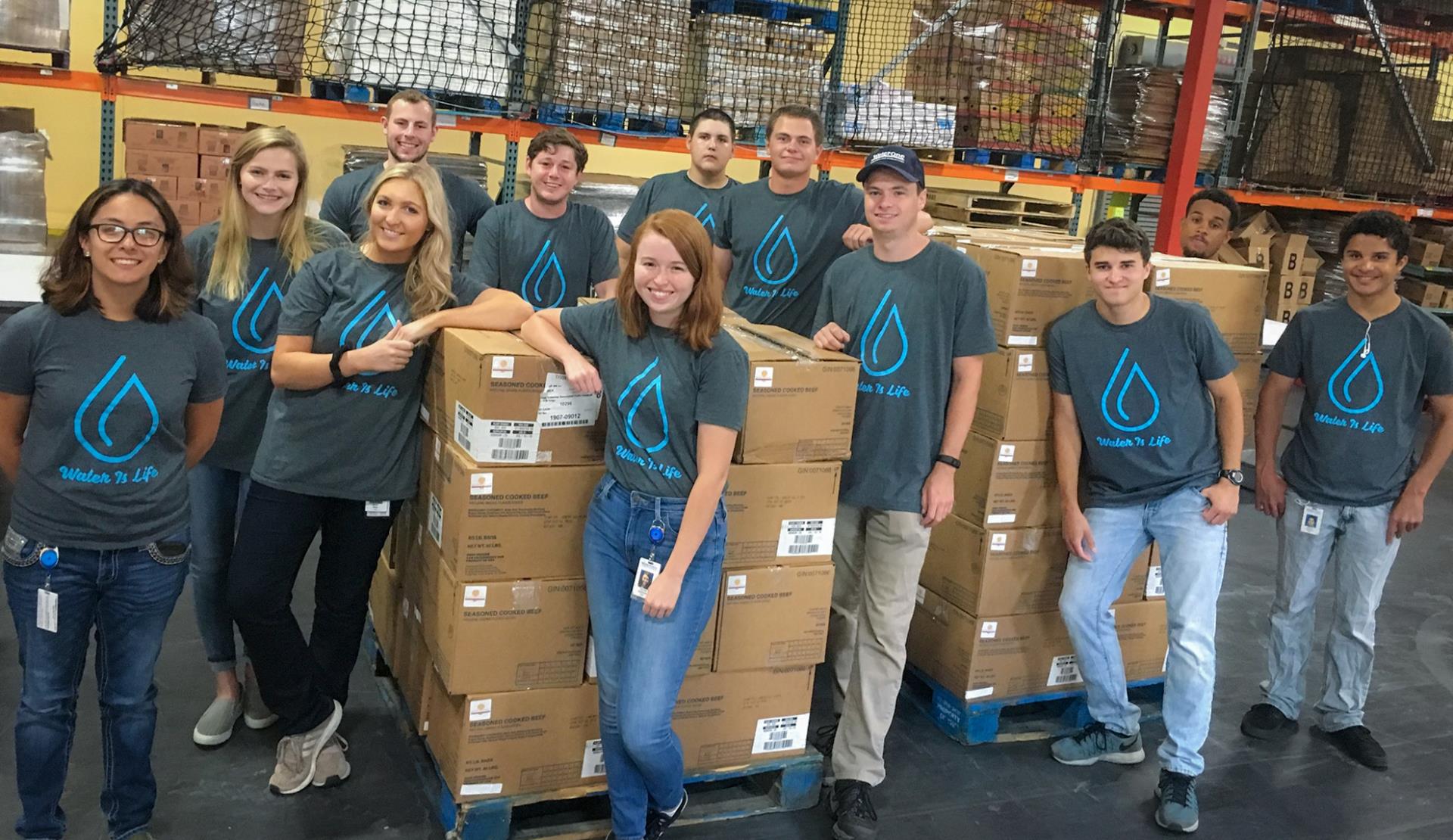 WaterOne Interns posing in a warehouse with stacked boxes